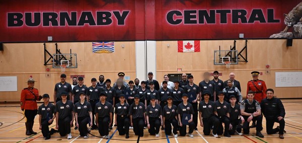 Un groupe d&rsquo;&eacute;l&egrave;ves de l&rsquo;&Eacute;cole de gendarmerie pour la jeunesse sourient dans le gymnase d&rsquo;une &eacute;cole.