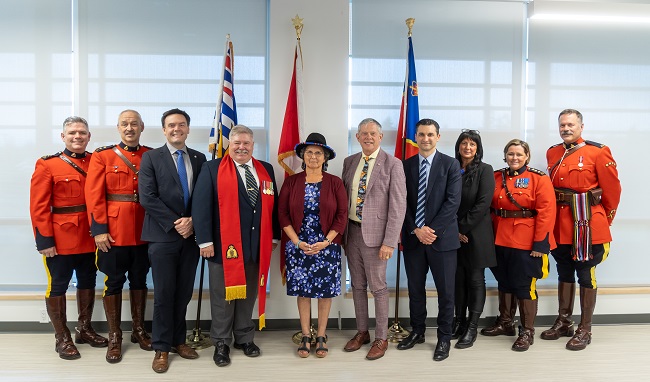 Group picture of VIPs and ceremony speakers with RCMP officers dress in ceremonial red serge.