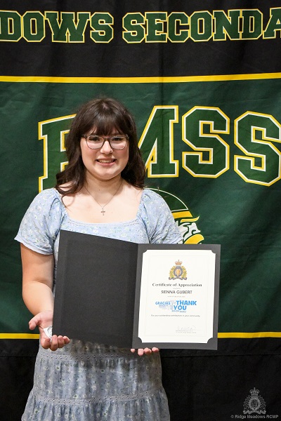 Sienna Gubert holding her RCMP LMD Challenge Coin and Certificate