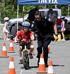 Emergency Worker teaching skills course to child on bike