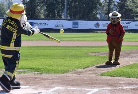 The Kamloops Fire Rescue mascot &lsquo;Sparky&rsquo;, (a dalmatian in a firefighter&rsquo;s uniform), takes a swing at a softball pitched by the Kamloops RCMP mascot, Sgt Safety Bear (a bear in a Mountie Serge and hat). 