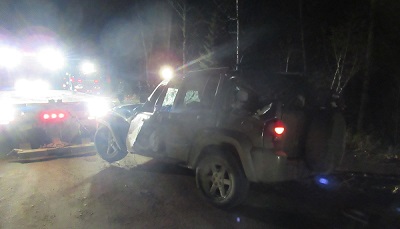 photo of a tow truck pulling a damaged Jeep Liberty onto a dirt road