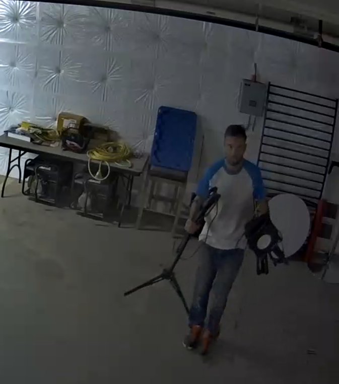 The suspect is a skinny Caucasian man with a beard, 20-30 years old, wearing a blue and white t-shirt, blue jeans, and red and black shoes