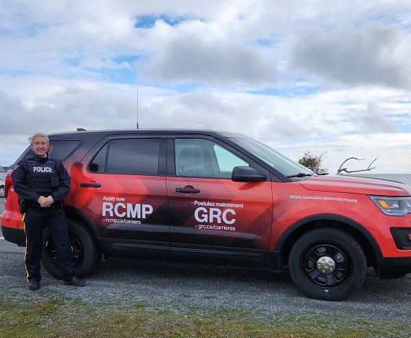 Photo of Cst. Sam Haldane in uniform standing next to her new recruiting vehicle. 