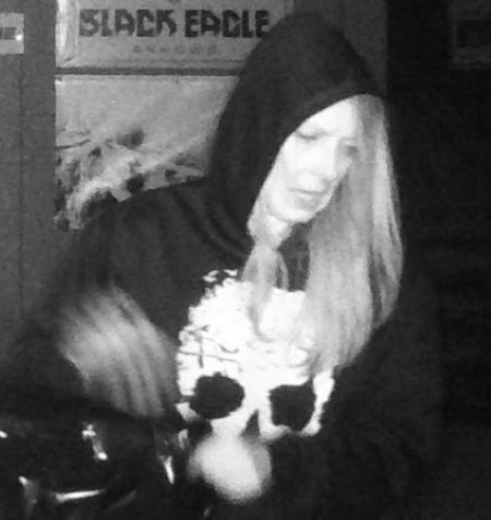 A woman with long hair in a hooded sweater with a skull on the foot.