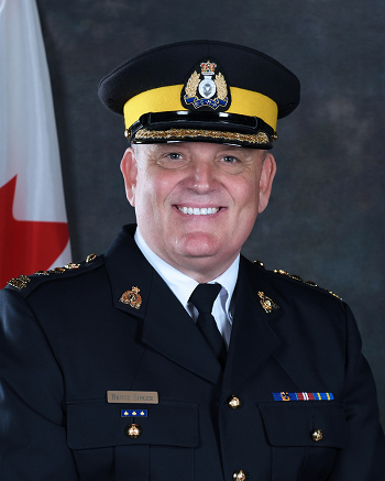 Photo of Chief Superintendent Bruce Singer smiling in police uniform with forge hat.