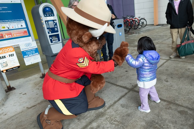 RCMP mascot Sgt. Bison giving a hih five to a small child. 