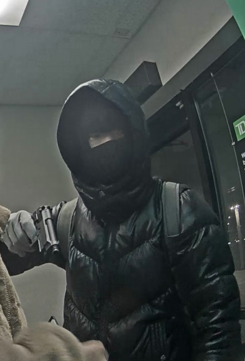 man in dark hooded jacked and face mask holding a gun