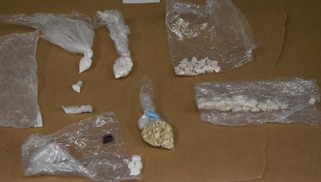 Various illicit drugs tied up in saran wrap and clear baggies.