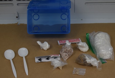 Various illicit drugs in clear baggies with two plastic white spoons.