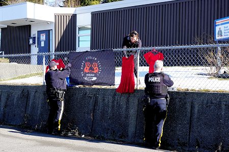 Photo of Sgt. Erin Stevenson, Alert Bay RCMP Detachment Commander; Anne Jackson, Detachment Service Assistant; and Cst. Bruce Verhaeghe, putting up a display outside of Alert Bay Detachment to showcase their support of the 5th annual healing gathering.