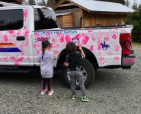 two children putting pink hand prints on police truck