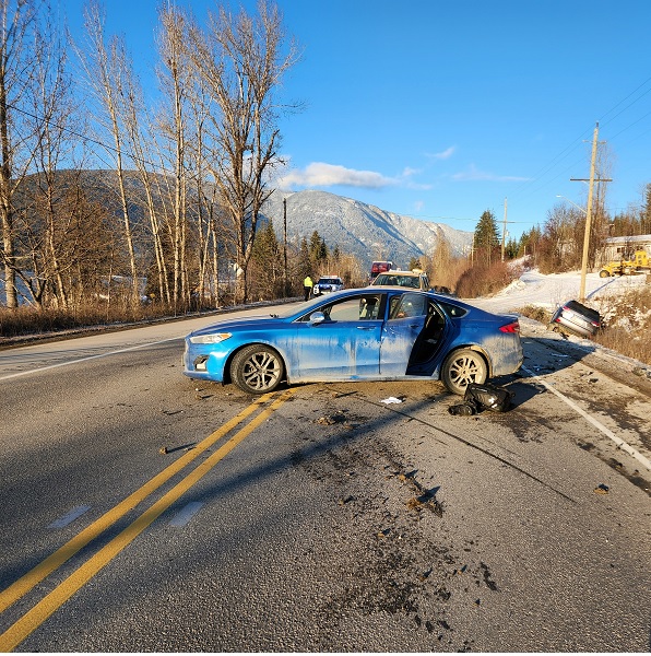 Blue Ford Fusion in middle of highway, with Lexus in the ditch