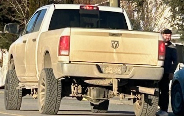 Man standing beside white Dodge Ram pick up