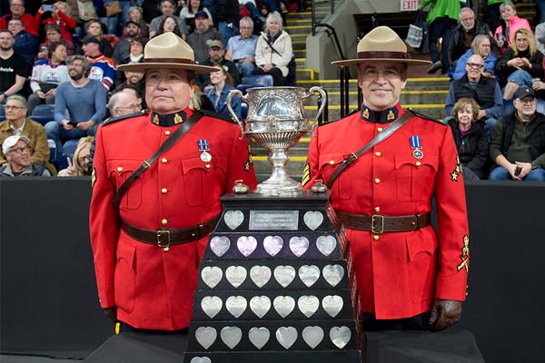 Photo of two RCMP officers in red serge carrying the Brier championship trophy