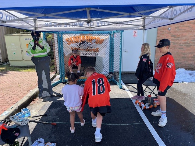 Semiahmoo Lacrosse players teaching a young girl how to use a lacrosse stick