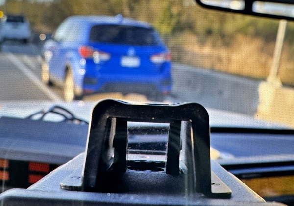 Un lecteur laser montre une vitesse de 157 km/h alors qu’une voiture bleue est arrêtée devant un véhicule de la Patrouille routière de la C.-B.