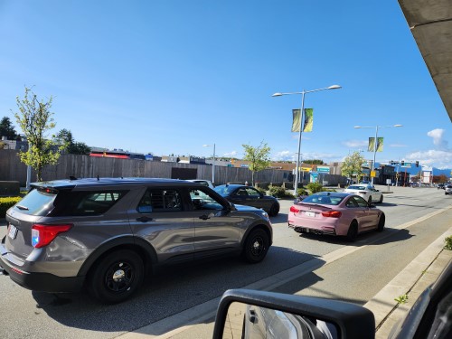 une voiture de police banalisée, immobilisée derrière une berline BMW rose.