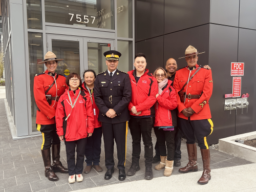 Chief Superintendent Dave Chauhan, Officer in Charge of Richmond RCMP, standing together with RCMP officers and volunteers in front of a building
