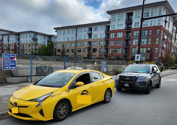 A taxi stopped at the side of the road with a BC Highway Patrol vehicle. The driver has received a 90-day Immediate Roadside Prohibition
