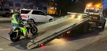 motorcycle being loaded onto flat bed tow truck]