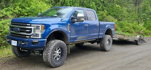 photo of blue 2022 ford f-350 truck and flatdeck trailer