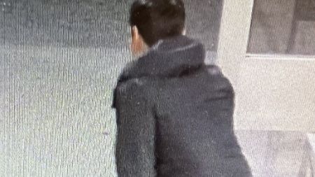 Photo du suspect de dos, tenant un sac rouge.