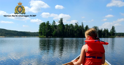 photo of young girl wearing an orange life jacket in a canoe on a lake