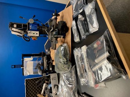 Une image en gros plan de certains des objets saisis, notamment des pistolets et une imprimante 3D.