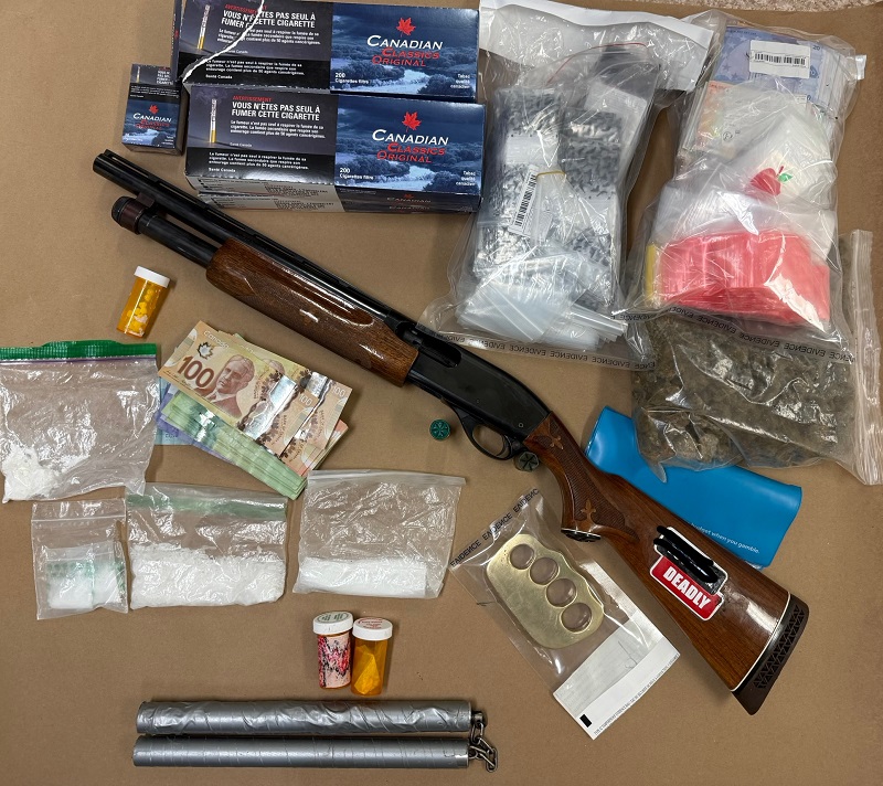 weapons, drugs, drug packaging materials, and illegal cigarettes laid out on a brown backround.  