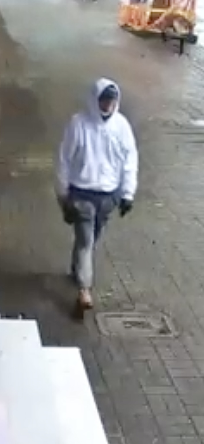 Photo of suspect wearing white hoodie, baseball cap, grey track pants, and brown shoes