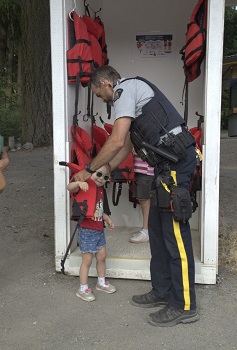Cst. Holditch helps a young child put on a lifejacket, ensuring a secure and safe fit