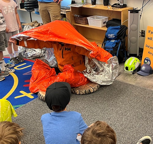 Photo d&rsquo;un membre de l&rsquo;&eacute;quipe de recherche et de sauvetage de Squamish sensibilisant les &eacute;l&egrave;ves d&rsquo;une &eacute;cole primaire locale &agrave; la s&eacute;curit&eacute; en plein air.