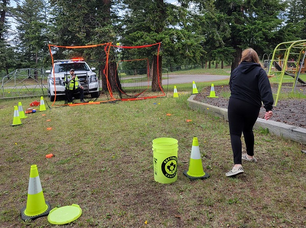 A BC Highway Patrol officer sits behind a net while using a radar gun to measure the speed of a Lac La Hache girl&rsquo;s pitch