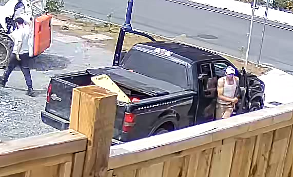 Photo of black truck and two suspects, one suspect walking away from the truck