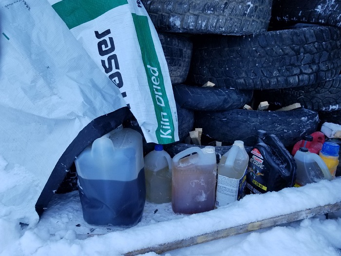 Photo of jugs of accelerants and kindling under stack of tires