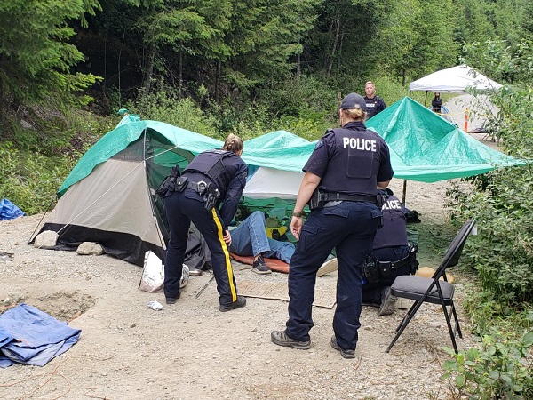 Individuals in locking devices on the ground, covered by tents and tarps