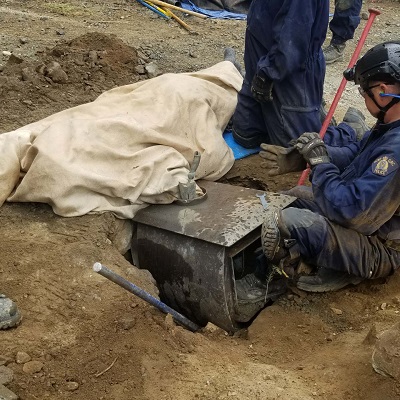 Image of a person with arm in a locking device inside a trench