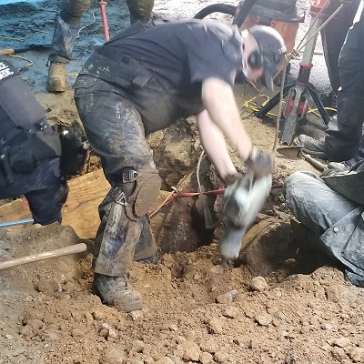 Photo of individual in trench that was filling with water.