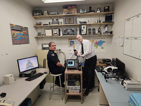 Photo of RCMP officer and Computer tech in a modern Radio Room in 2023.