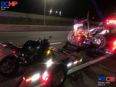 Photo of two motorcycles secured to a towing dolly behind a tow truck