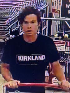 Un suspect pousse un chariot &agrave; l&rsquo;int&eacute;rieur du magasin. Il porte un t shirt noir orn&eacute; de l&rsquo;inscription &laquo; Kirkland &raquo; en blanc &agrave; l&rsquo;avant. Il a des cheveux bruns courts peign&eacute;s sur le c&ocirc;t&eacute;.