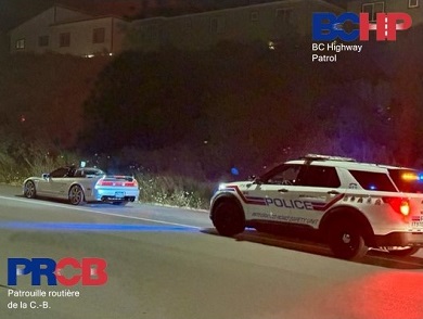 Vue lat&eacute;rale d&rsquo;un v&eacute;hicule identifi&eacute; du GISR gar&eacute; derri&egrave;re une voiture de sport grise sur l&rsquo;accotement de la route.