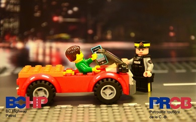 voiture en Lego avec conducteur tenant un t&eacute;l&eacute;phone, agent de la GRC en Lego debout pr&egrave;s de la voiture