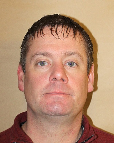 Daen Rakose with short brown hair, cleanly shaven wearing a red collared sweater