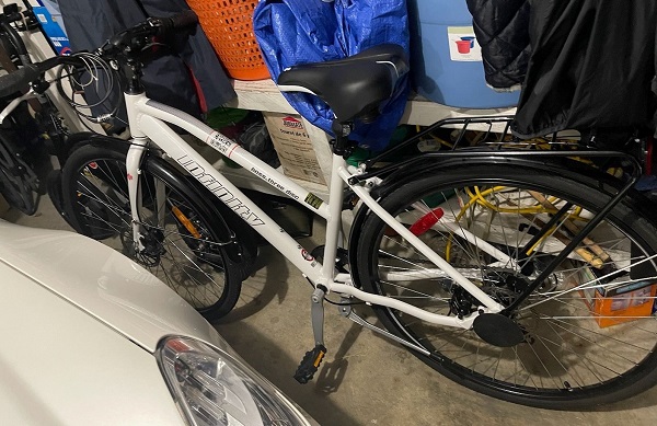 Photo of Narinder Sandhu&rsquo;s white Infinity mountain bike with black storage rack on the back and the word Infinity branded on the main frame of the bike.