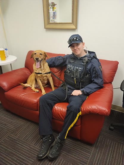 A North Vancouver RCMP officer sits with Amber the golden retriever, stolen outside of a business in Central Lonsdale.